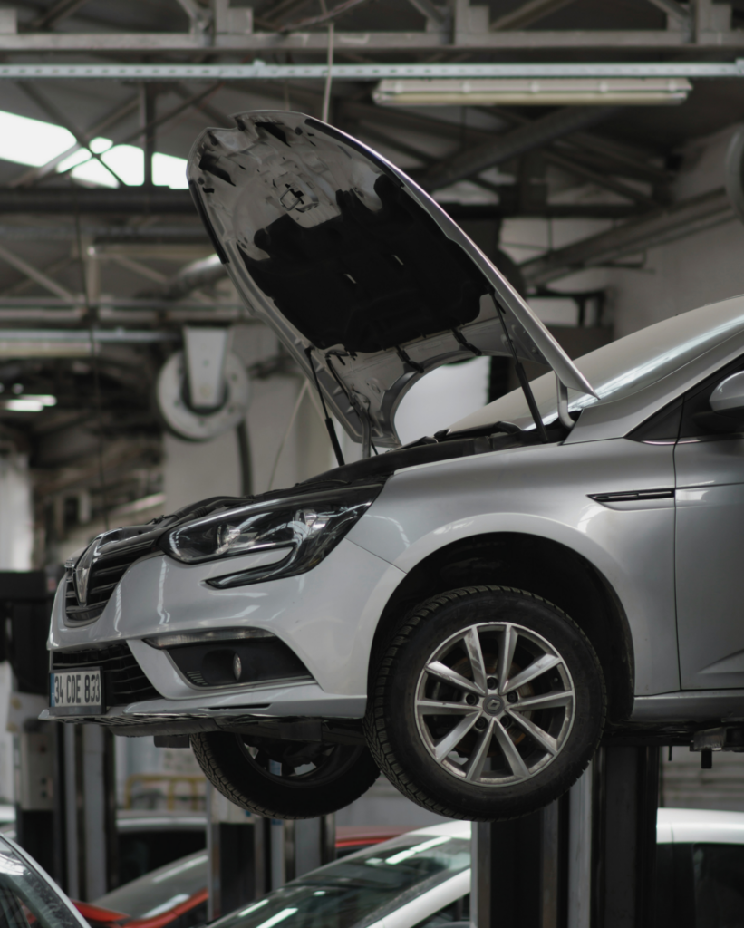 auto s otvorenou kapotou na stroji v autoservise